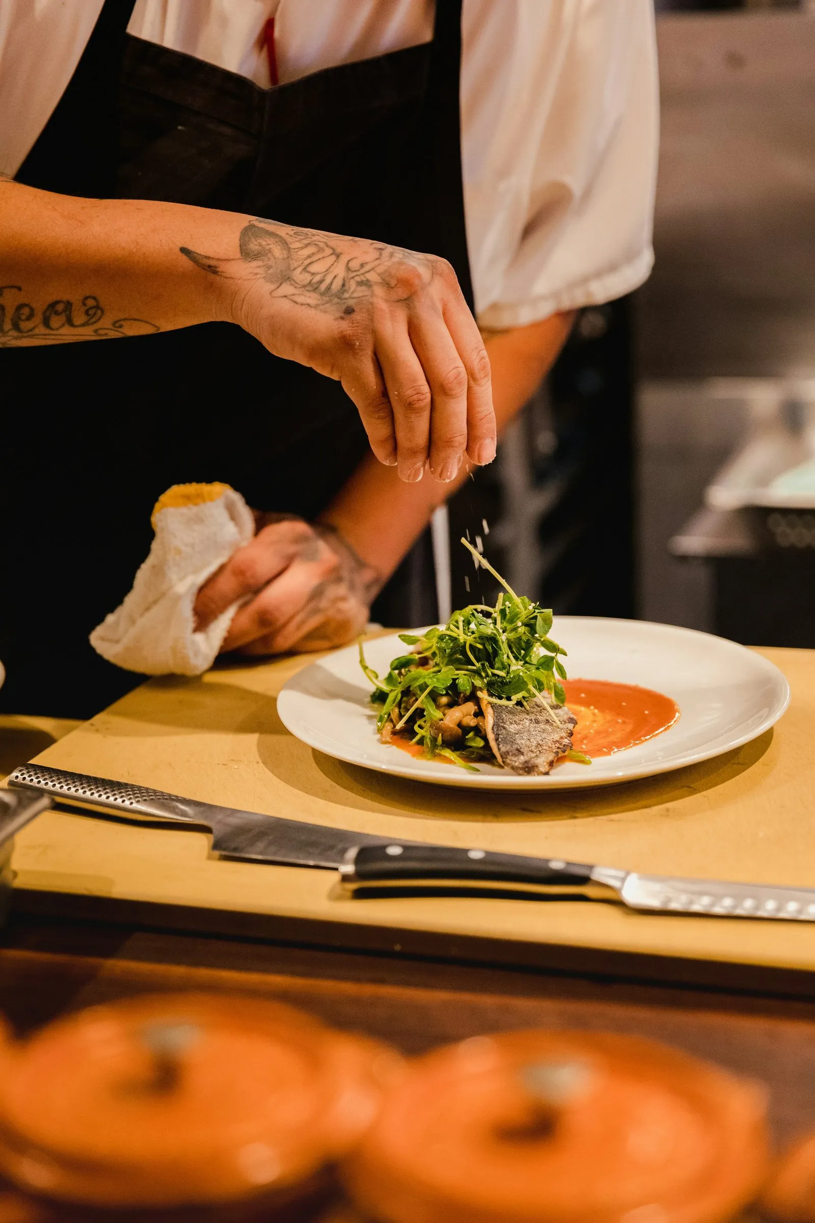 A chef plating a dish in an open kitchen